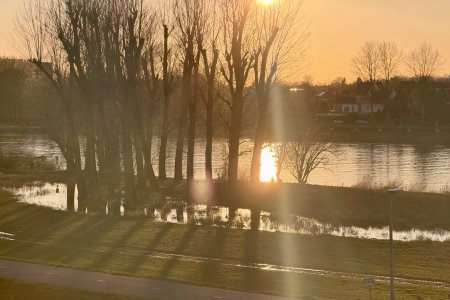 De zon gaat onder boven de Maas